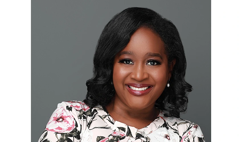 photo of a dark skinned woman in a floral top looking at the camera